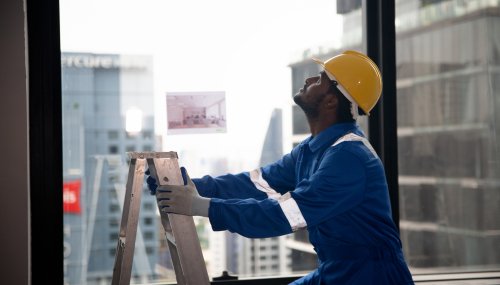 Mature man on construction site Builder or foreman in working uniform expertising the structure standing with folder at the construction site indoors