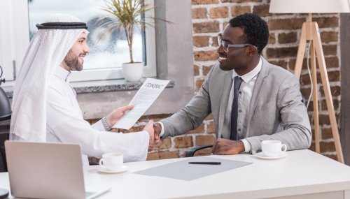 Multiethnic businessmen shaking hands and smiling in office Multiethnic businessmen shaking hands and smiling in office